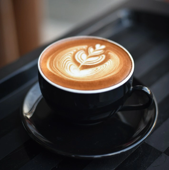 Café en una taza negra con arte latte