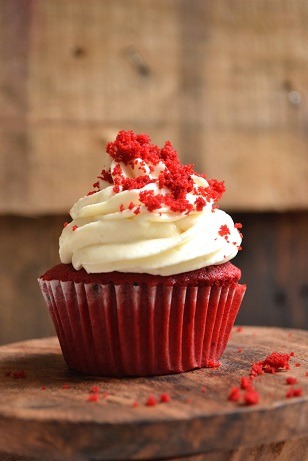 Cupcake de bizcochuelo rojo con crema de chocolate blanco y decoración en rojo